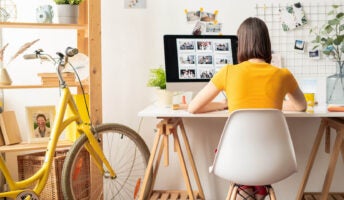 Woman works remotely at desk next to yellow bicycle