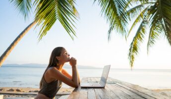 Female digital nomad working remotely from beach
