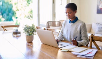 Young woman sits at home running online business from kitchen table