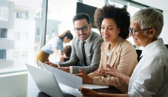 A group of three racially diverse employees looking over papers at a desk