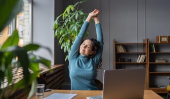 Woman stretching and looking happy at her desk