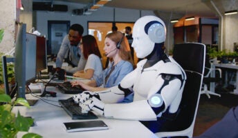 Robot sitting at desk alongside human employees illustrating AI in the workplace