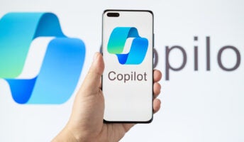 Hand holding smartphone featuring Microsoft Copilot logo against Copilot AI background