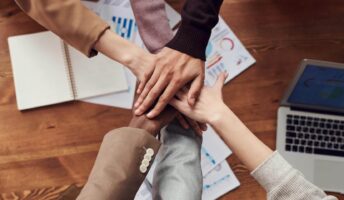 A diverse group of hands in an office setting.