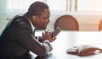 Man talking into phone in conference room with conference telephone on desk