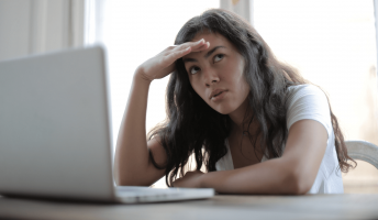 a woman looks annoyed in front of a laptop - women fared worse than men for online civility in 2021 according to microsoft